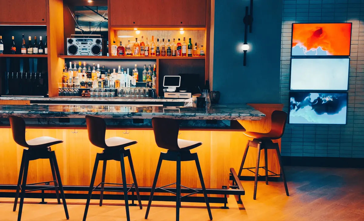 A warmly lit Culver City bar with stools along a polished counter