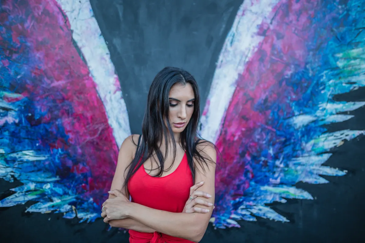 A visitor standing before a colorful wings mural in Culver City