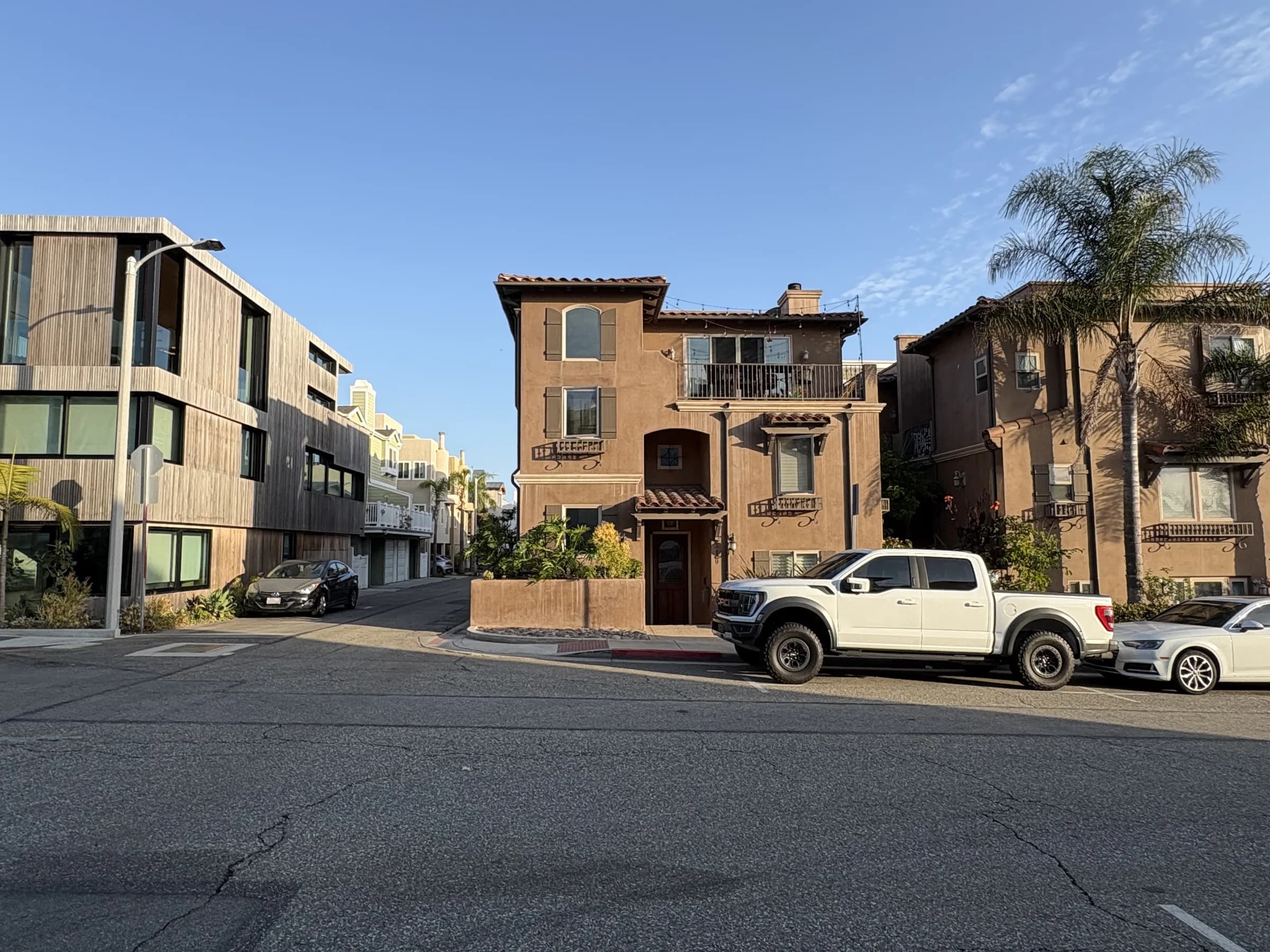 Warm stucco residences and palms at a Hermosa Beach intersection