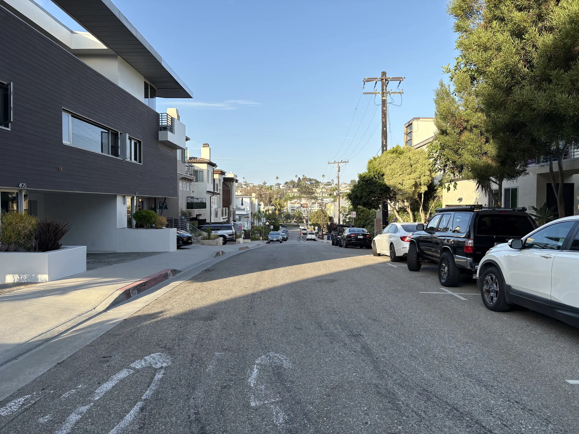 A lived-in residential street with hillside homes in the distance