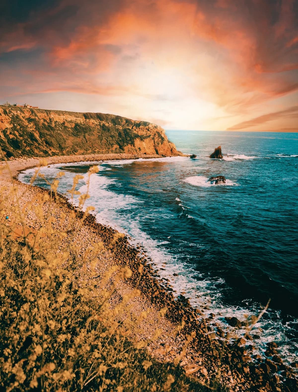 A rocky Palos Verdes bluff glowing beneath a dramatic sunset sky