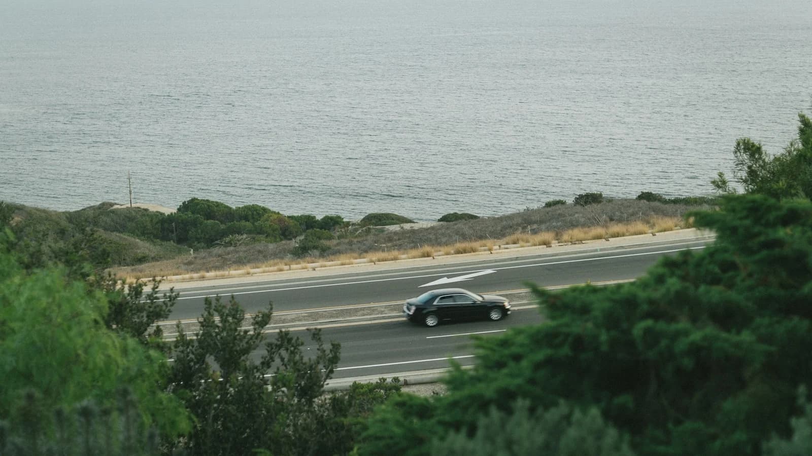 A car following a quiet coastal road above the Pacific