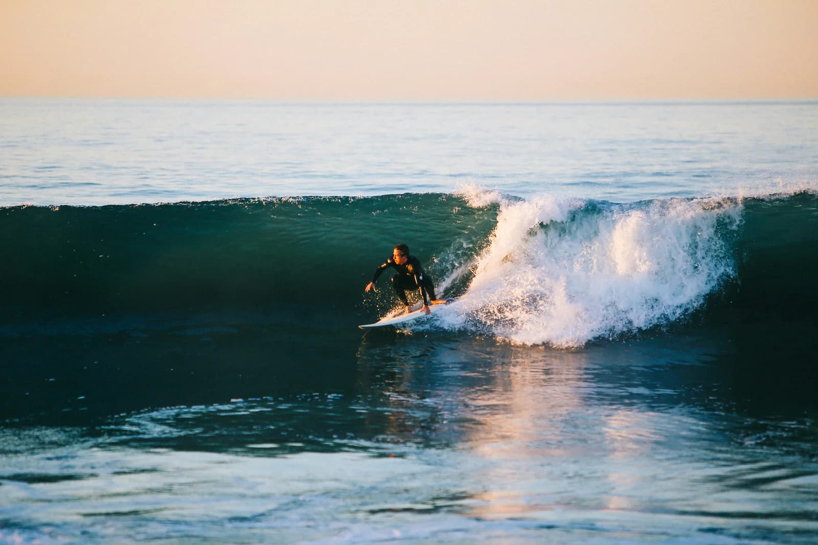 A surfer riding a moderate Southern California wave at sunset