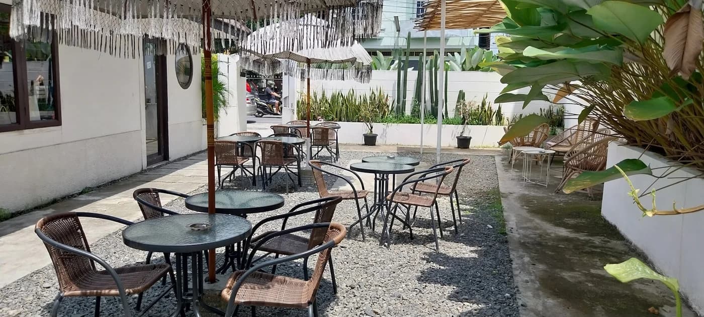 A garden cafe patio with tables beneath leafy shade