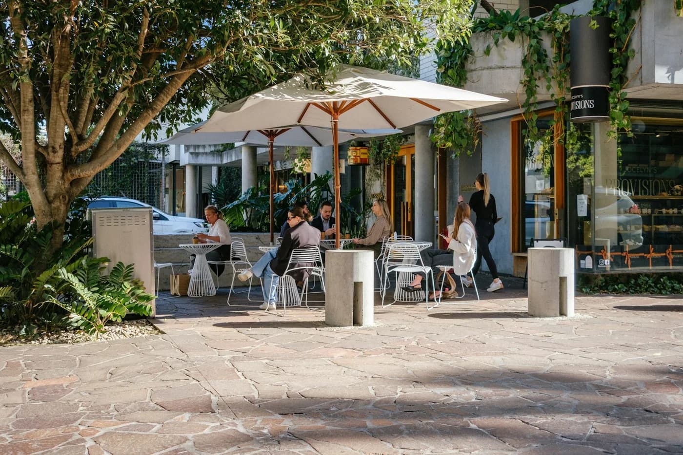 People dining beneath umbrellas at an open-air neighborhood cafe