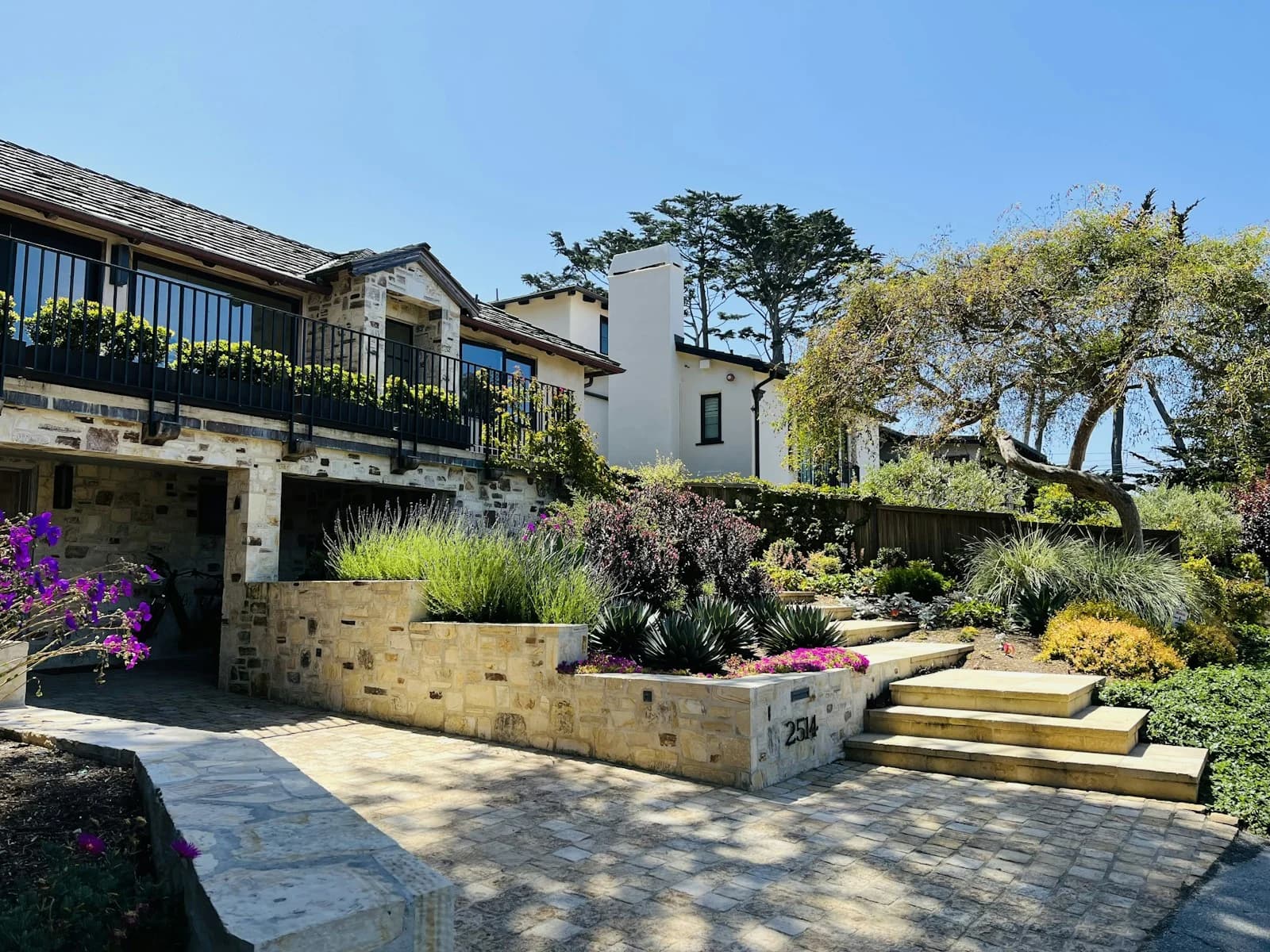 A landscaped Mediterranean-style home with stonework and a tiled roof