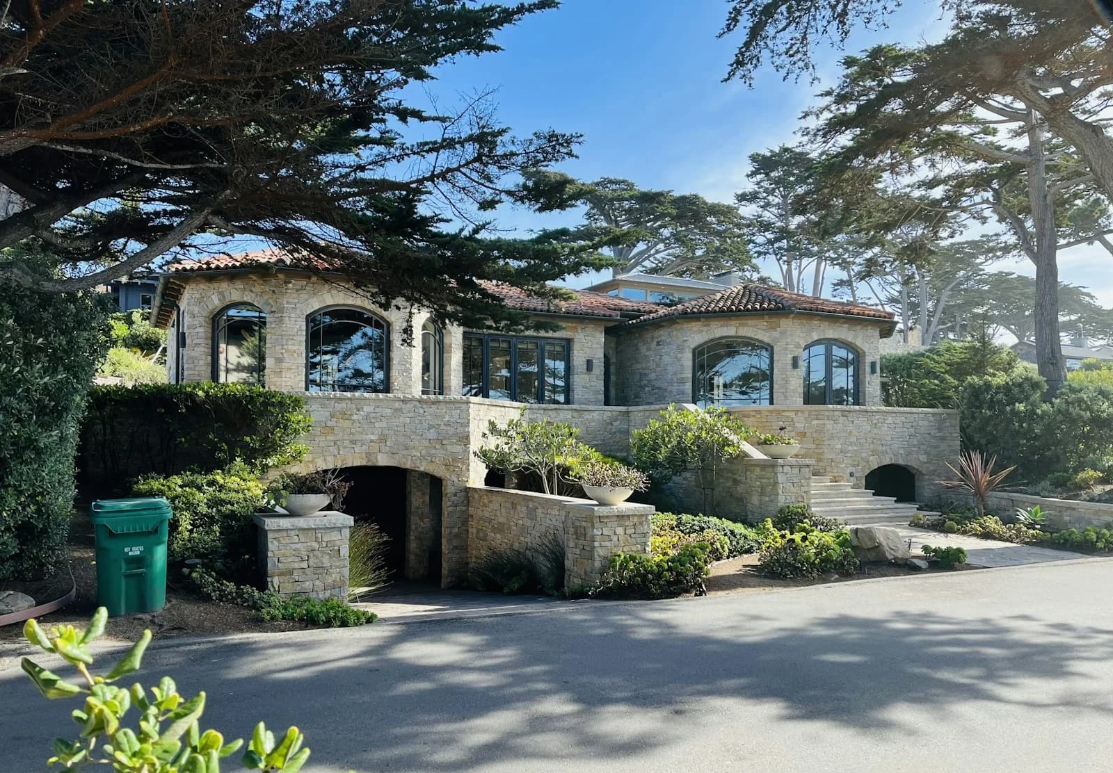A stone Mediterranean-style residence beneath mature coastal trees
