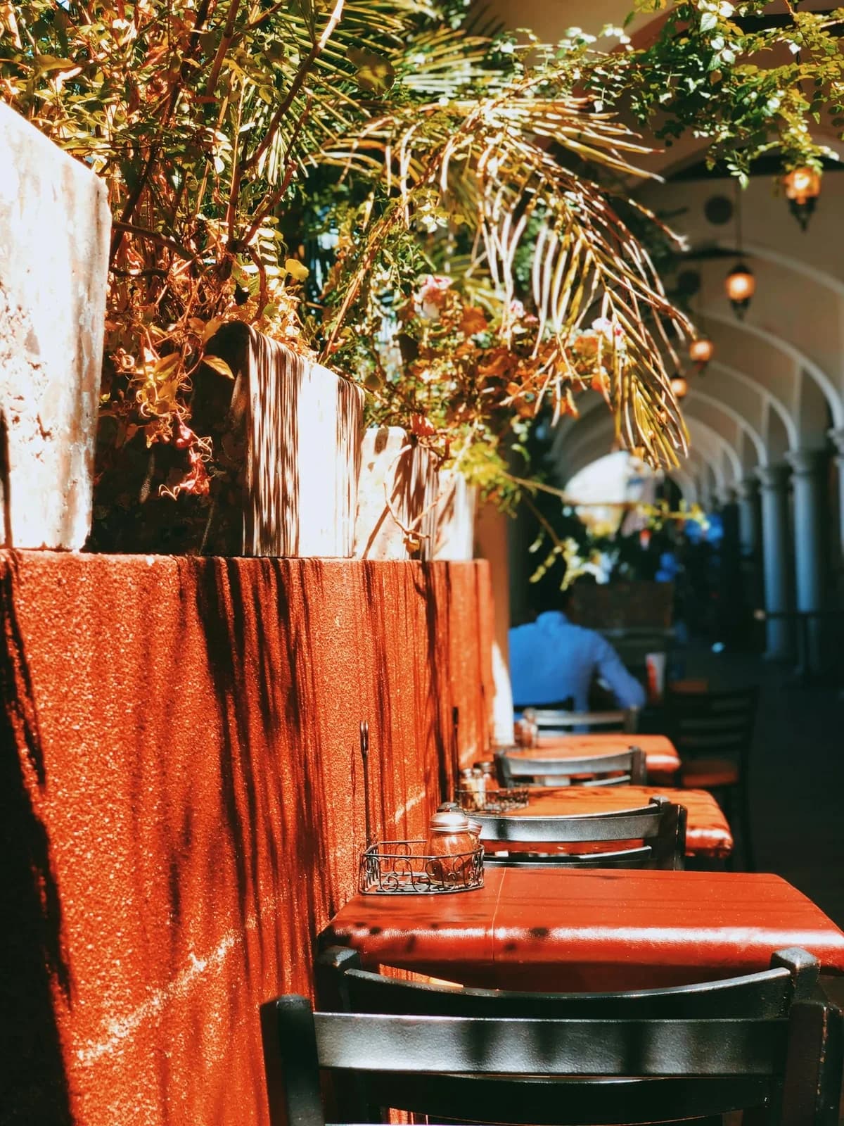 A shaded outdoor café terrace set for neighborhood dining