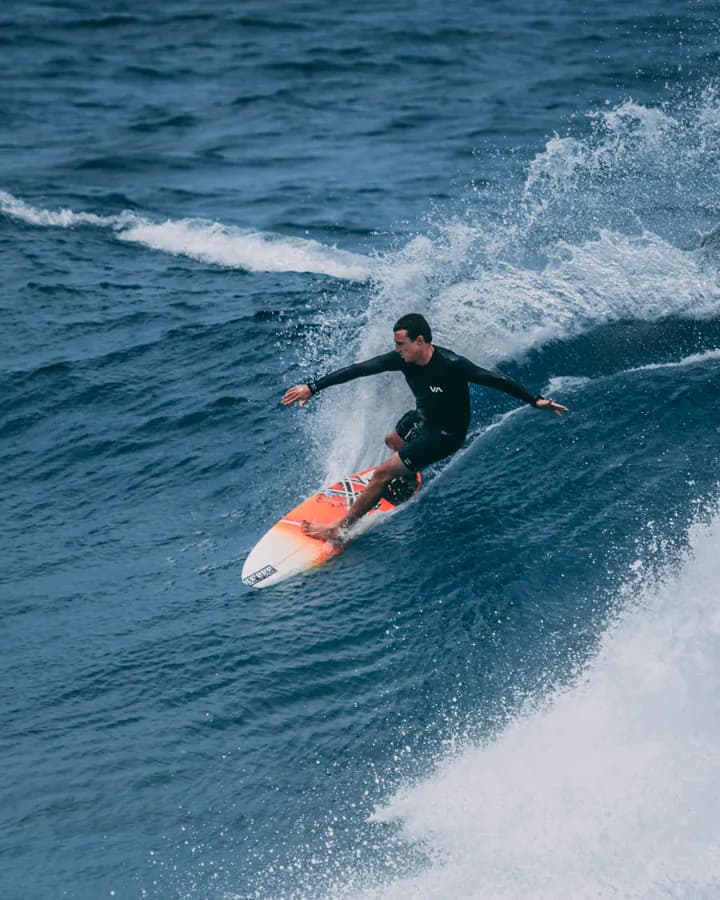 Surfer riding a blue wave on a red surfboard