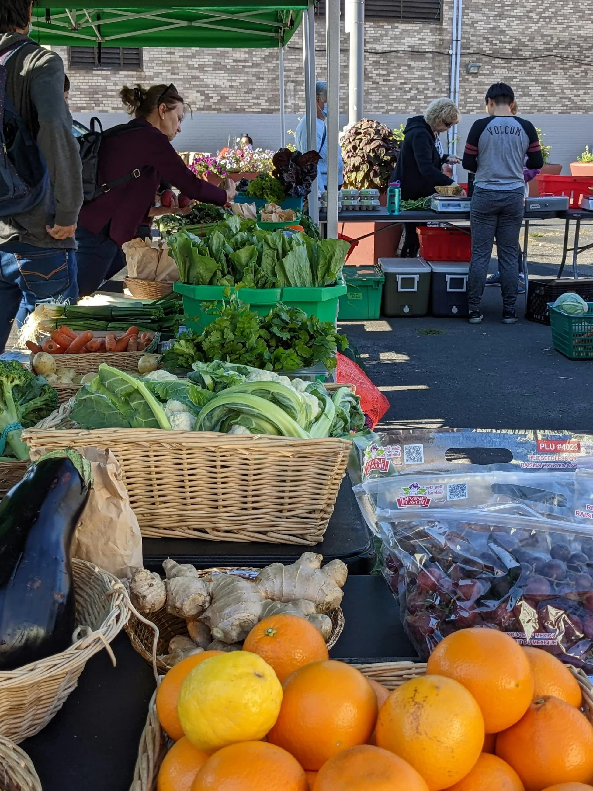 Fresh produce and shoppers at an outdoor farmers market
