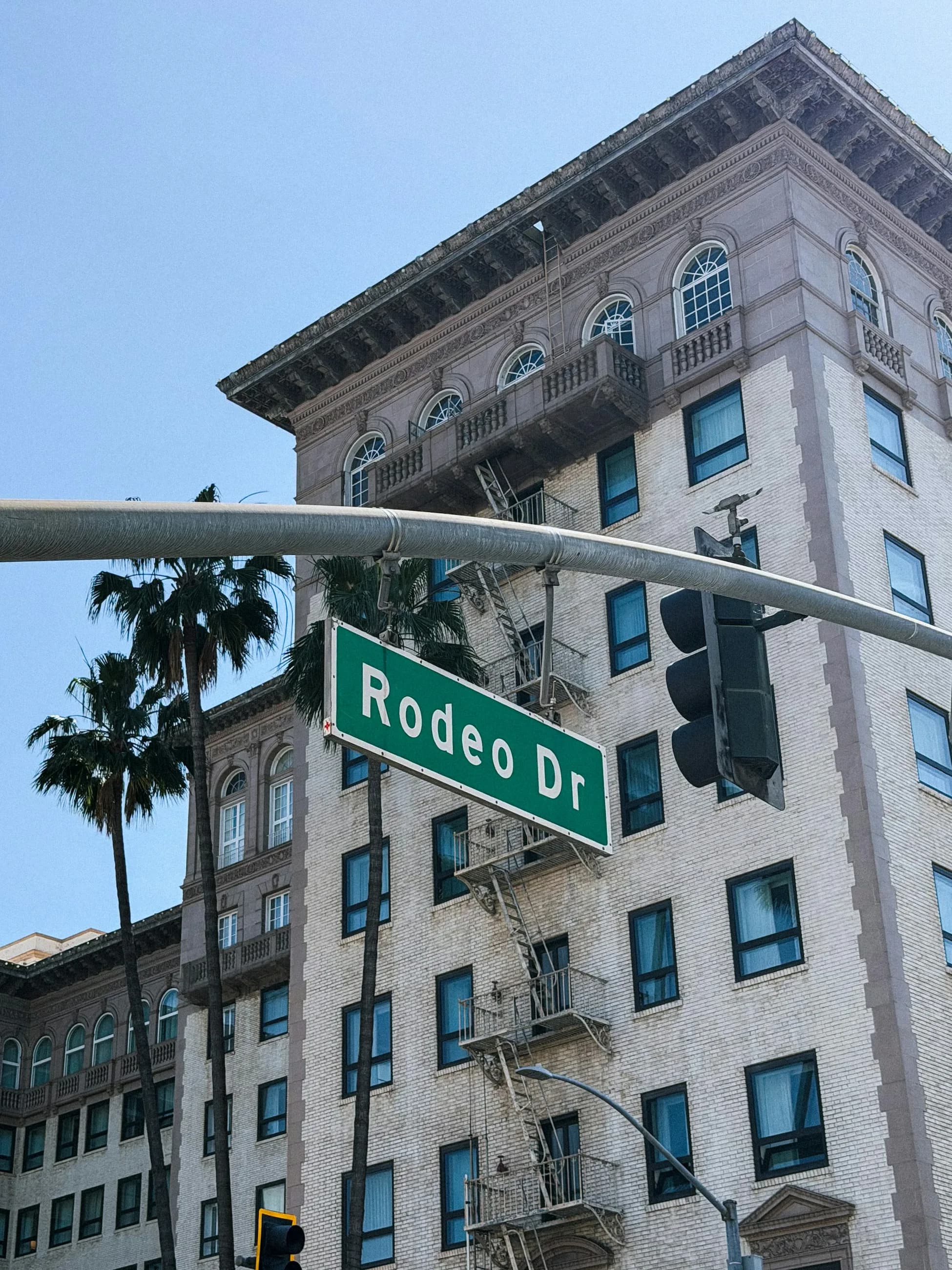 A Rodeo Drive street sign against a historic stone facade