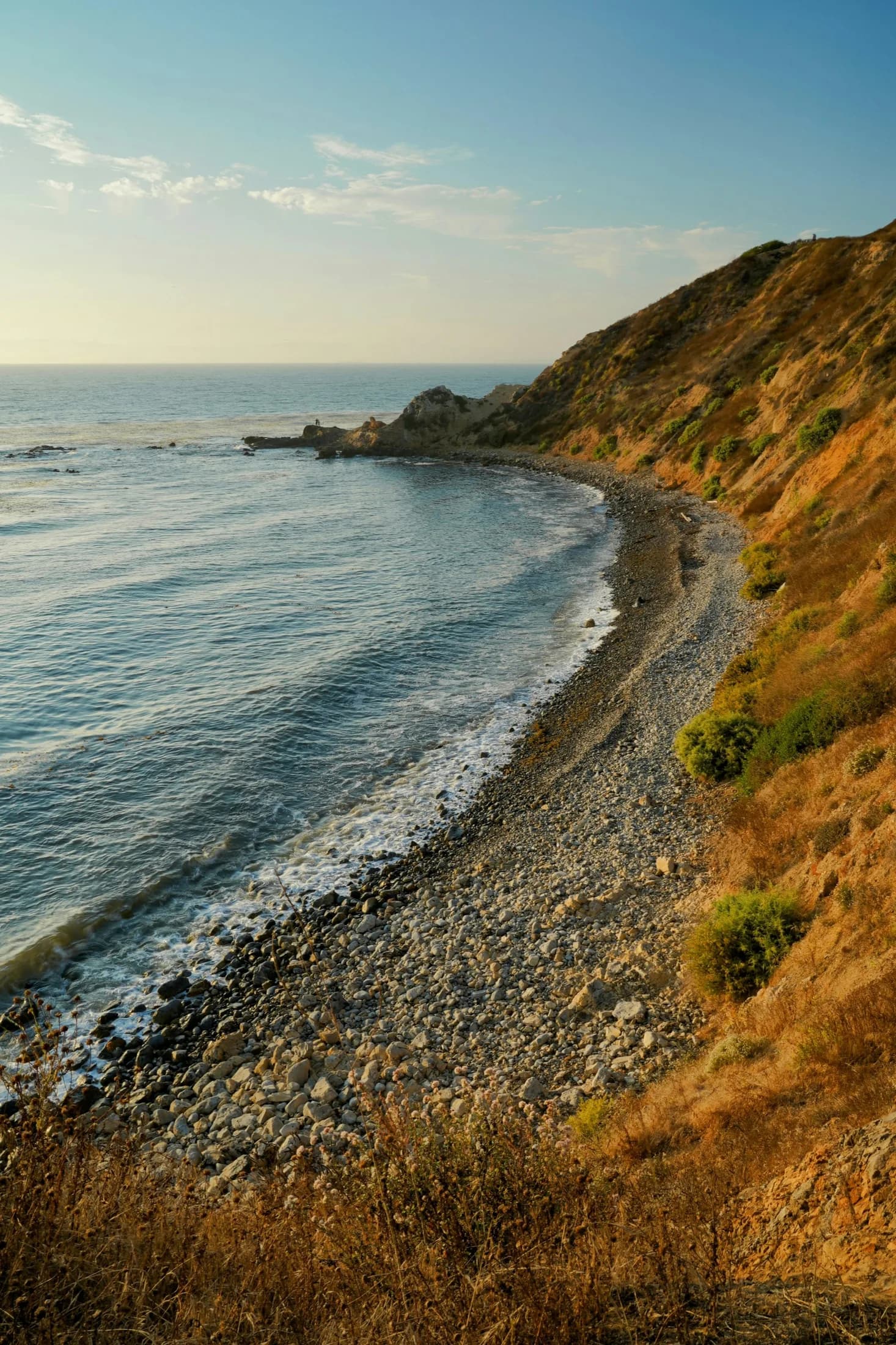 A narrow rocky beach curving below a Palos Verdes headland