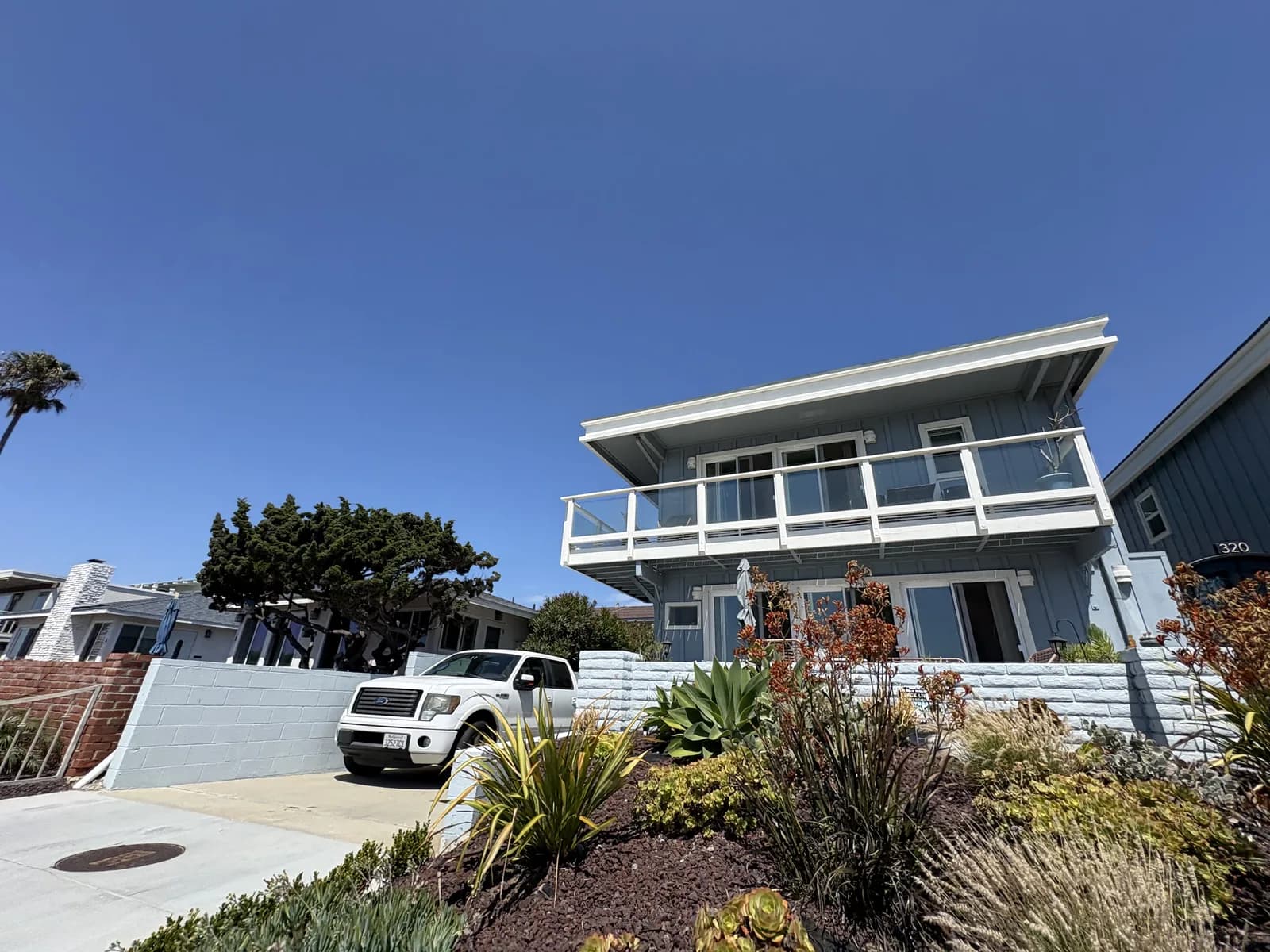 Blue-gray beachside home framed by drought-tolerant landscaping