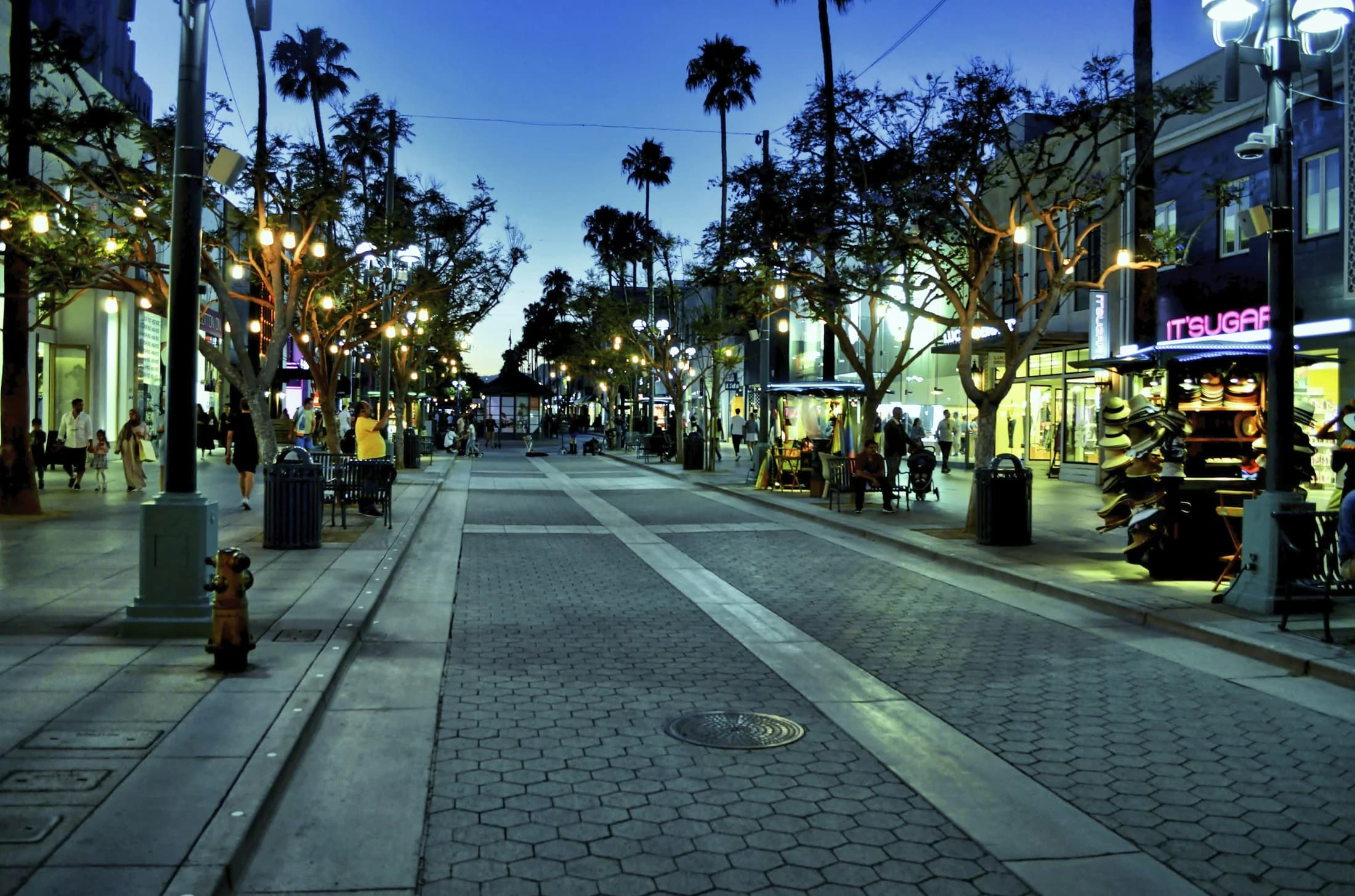 A lively pedestrian shopping street in downtown Santa Monica at dusk