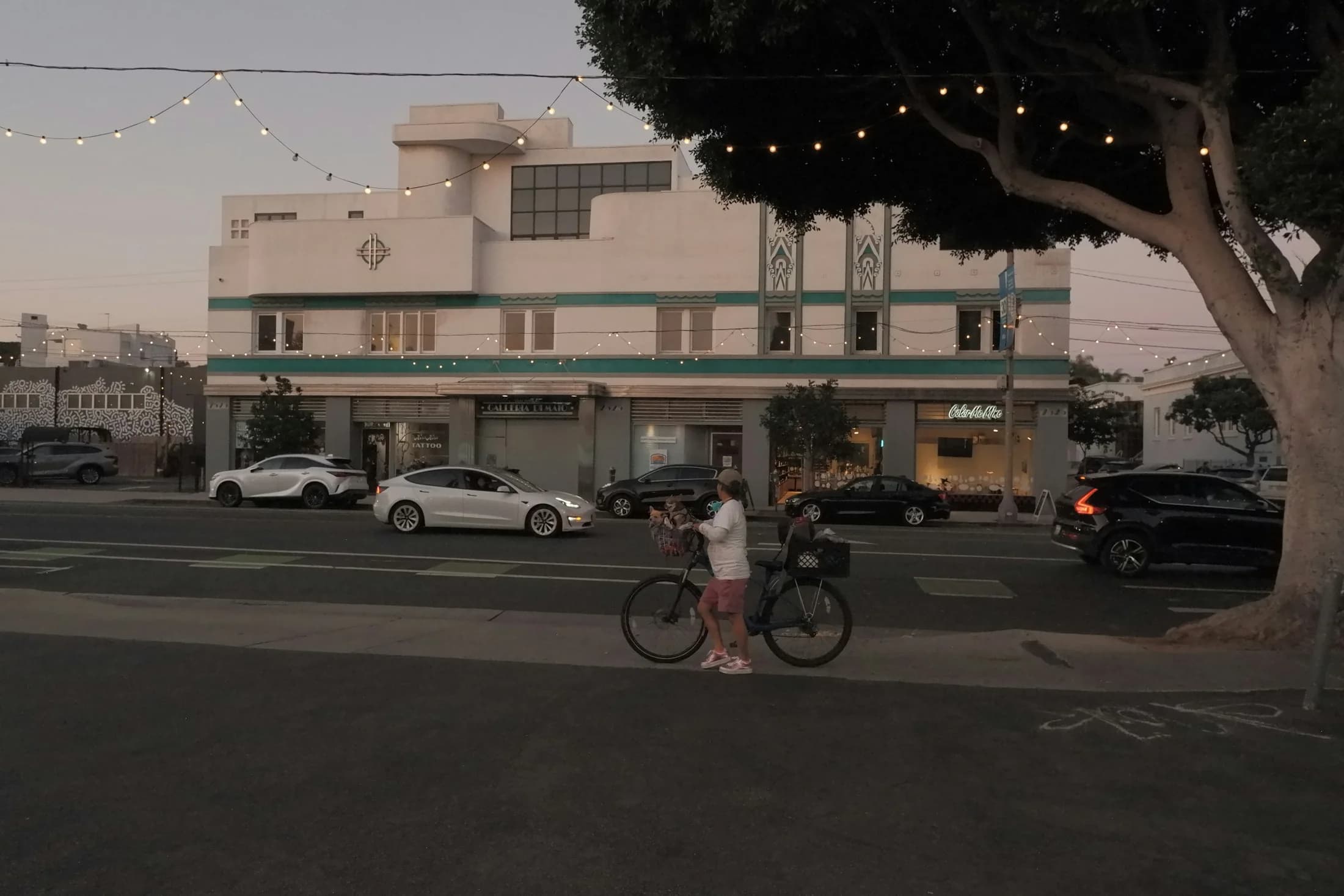 A cyclist passing neighborhood storefronts on a Santa Monica street