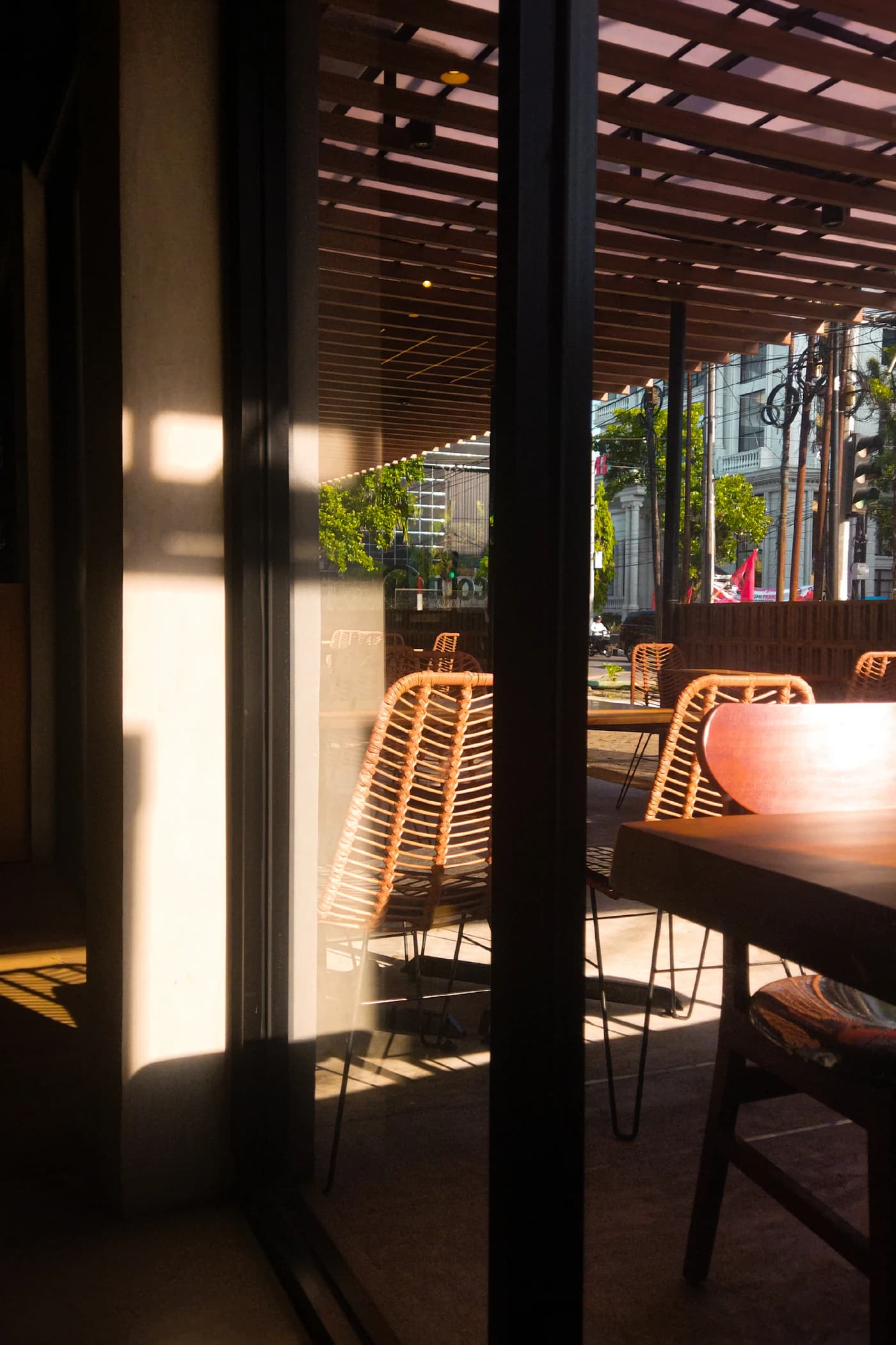 A sunny café patio framed by warm wood and greenery