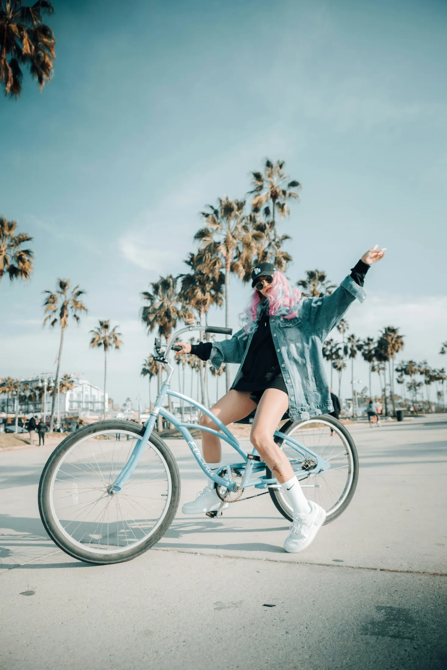 A cyclist riding across Venice Beach beneath scattered palms