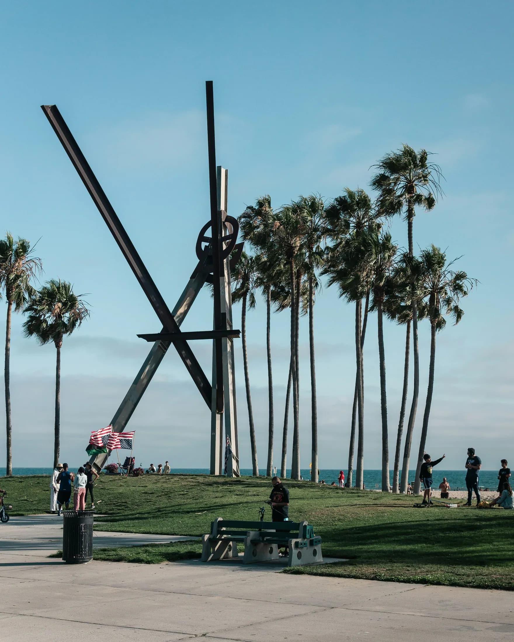 A public sculpture rising among palms near the Venice beachfront