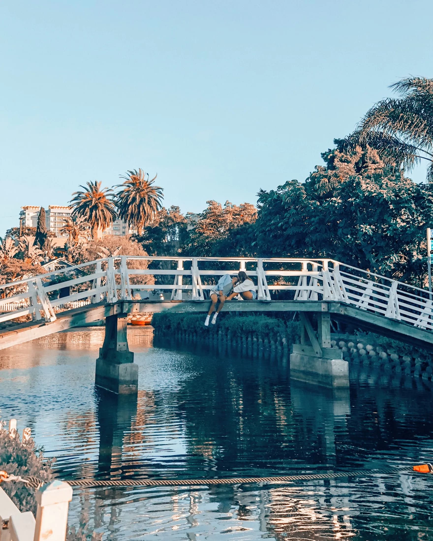A white pedestrian bridge spanning the calm Venice Canals
