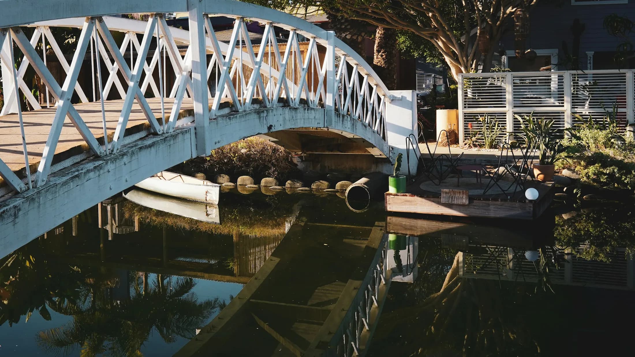A narrow white footbridge arcing over a shaded Venice canal