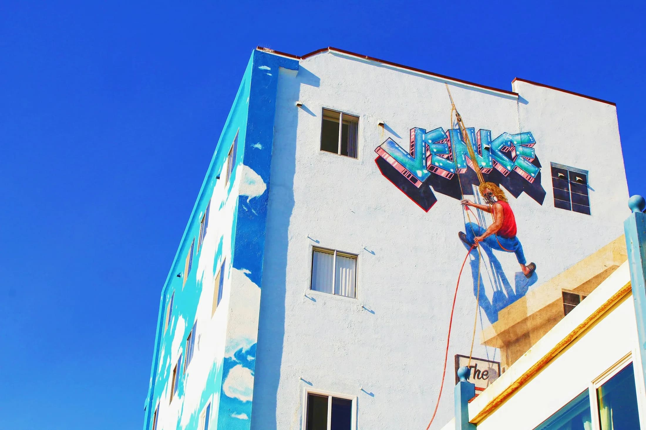 A mural artist painting a bright Venice-themed wall