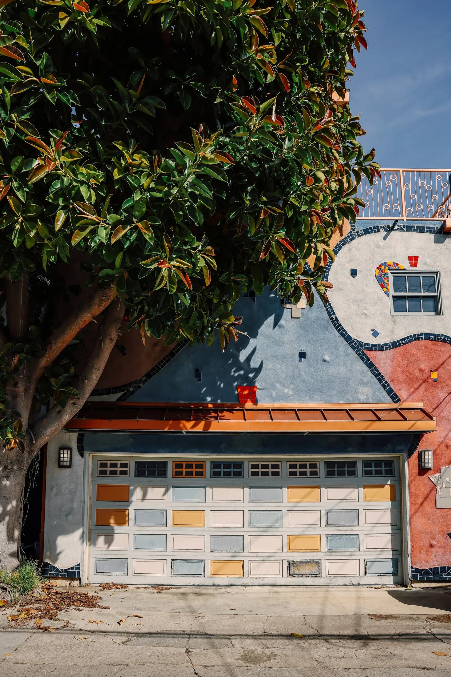 A colorful garage facade beneath a leafy tree at a Venice canal home