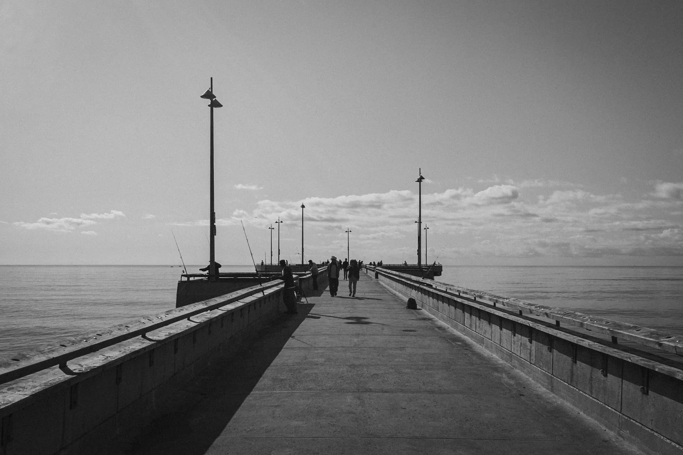 People walking toward the horizon along Venice Pier