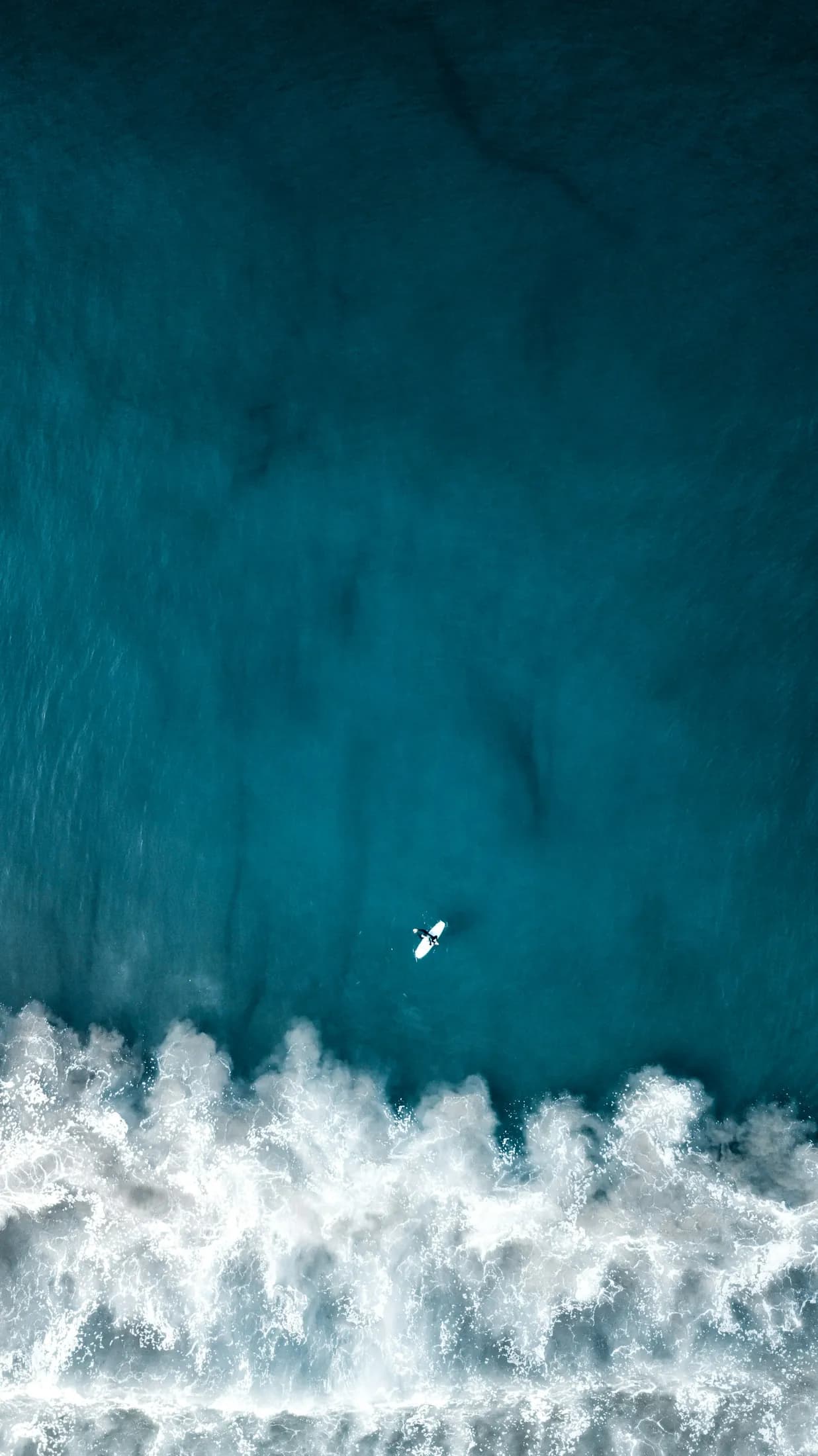 A lone surfer crossing a small line of whitewater off Venice Beach