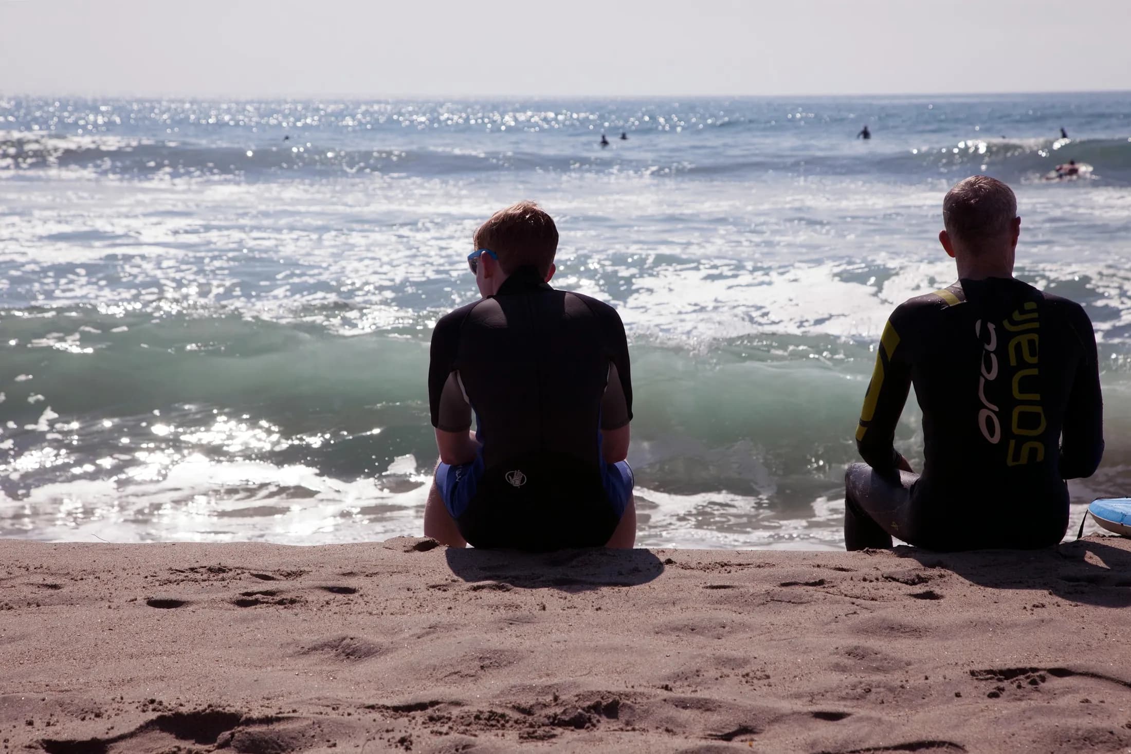Two surfers watching modest waves from the sand at Venice Beach
