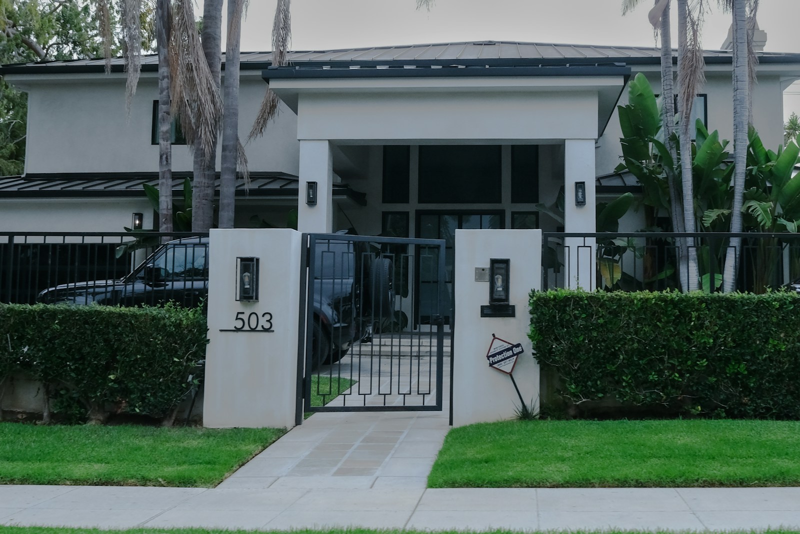A modern residence screened by a private gate and landscaping